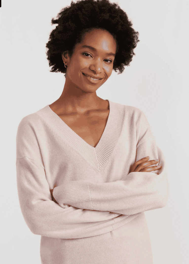 Woman wearing a pink v neck sweater.